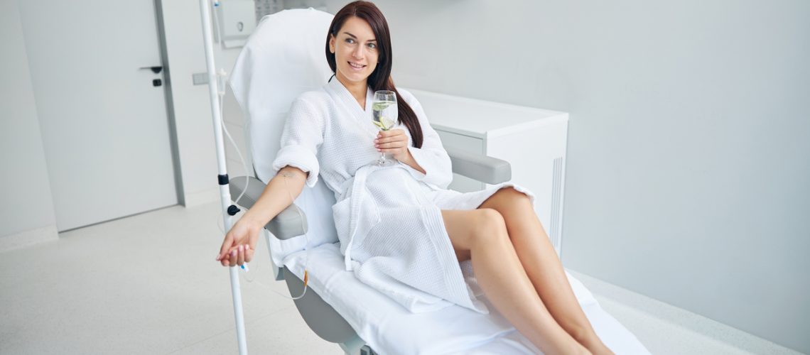 Smiling spa client with a drink staring away
